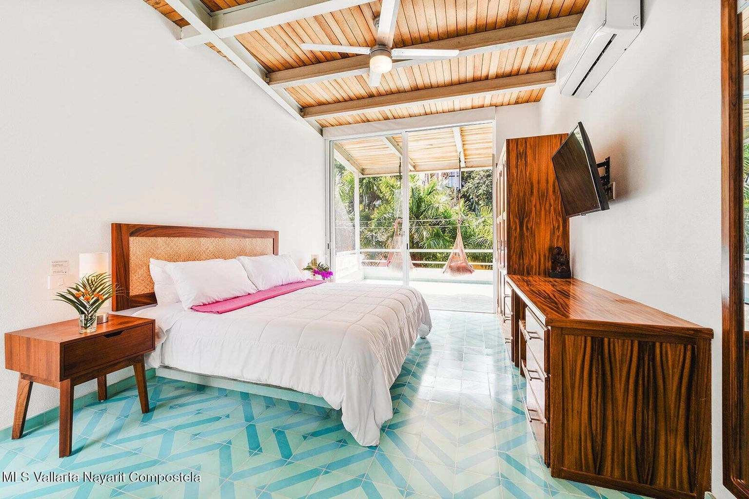 Elegante dormitorio en Casa Palmazul, Sayulita, con cama grande, ropa de cama blanca, decoración tropical y ventana que deja entrar abundante luz natural, creando un ambiente acogedor y relajante.