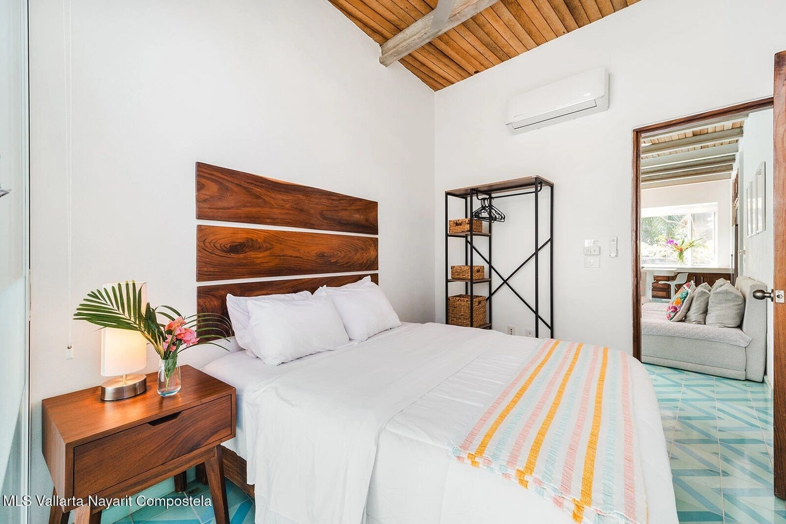 Bright and airy bedroom at Casa Palmazul in Sayulita, featuring a large bed with white linens, tropical decor accents, a window letting in natural light, and a relaxing, serene atmosphere.