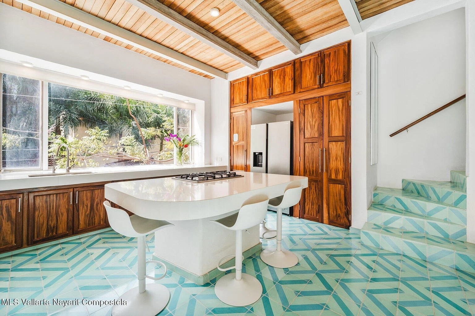 Modern, open kitchen at Casa Palmazul in Sayulita with sleek countertops, wooden cabinetry, stainless steel appliances, and bright natural light creating a welcoming cooking space.