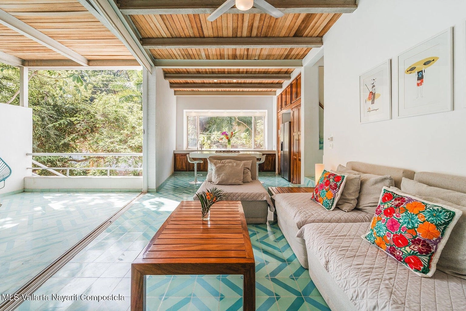 Amplia y luminosa sala en Casa Palmazul, Sayulita, con sofás cómodos, mesa de centro, decoración tropical y ventanales que permiten la entrada de luz natural, creando un ambiente relajante y acogedor.