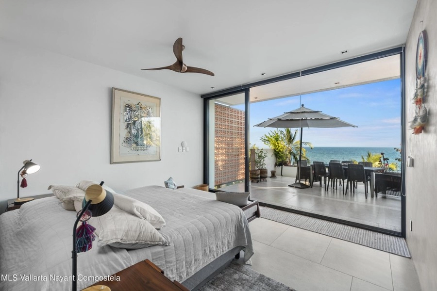 Primary bedroom with panoramic ocean views and balcony access