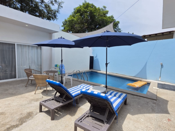 Casa Taya for sale in Sayulita, Nayarit, Mexico, featuring a modern single-story home with white and blue exterior, spacious parking area, and mature tropical trees.